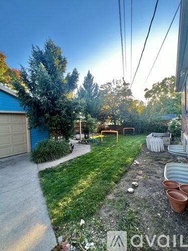 A backyard with a blue garage, a tree, and a fence.