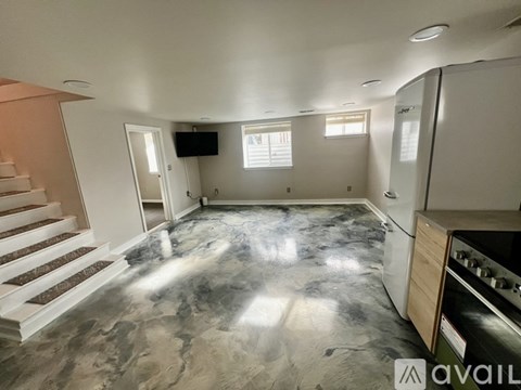 A kitchen with a marble floor and a staircase on the left side.