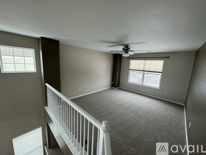 A spacious room with a ceiling fan and two windows.