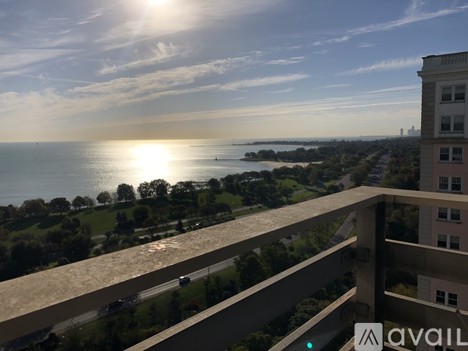 A balcony overlooks a body of water with a sunset in the distance.