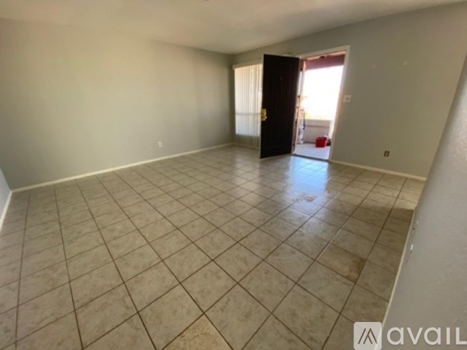 A spacious room with beige tiled flooring and a doorway leading to another room.