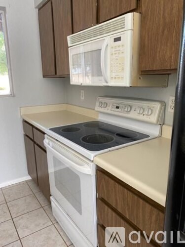 A kitchen with a white stove top oven and a white microwave above it.