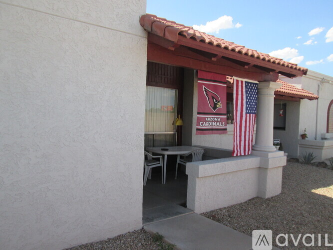 A patio area with a table and chairs is covered by a red awning.