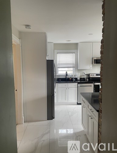 A kitchen with white cabinets and a black countertop.
