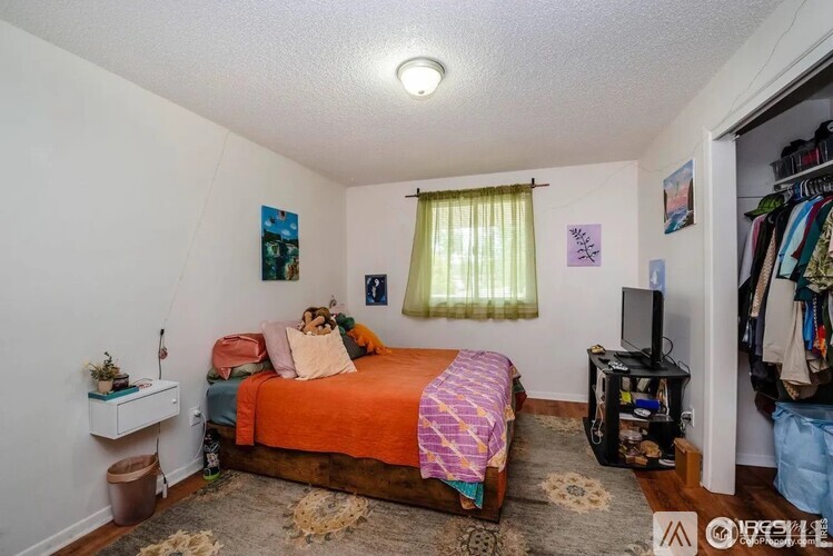 A bedroom with a bed, a dresser, and a closet.