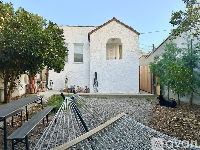 A white house with a grey roof and a small garden in front.