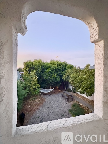 A view from a window looking out to a gravel area with trees.
