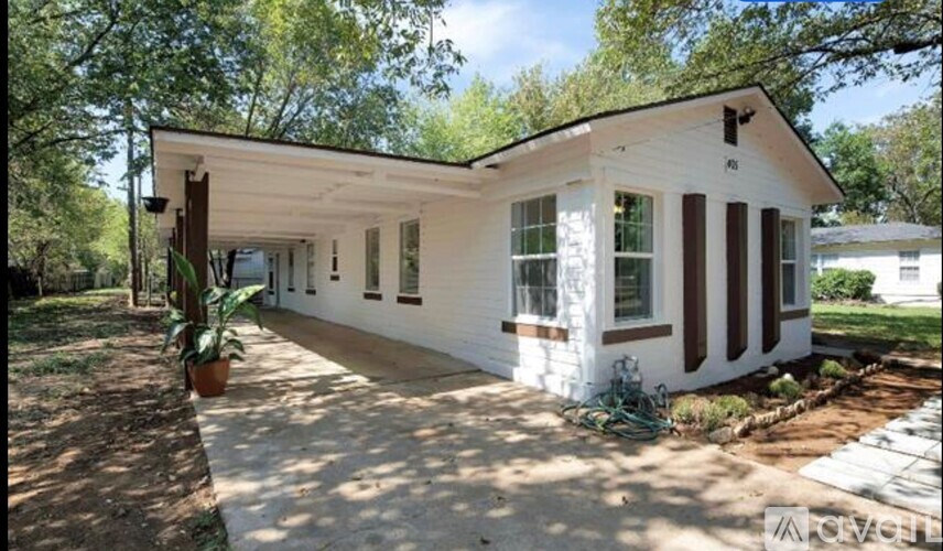 A white house with a brown roof and a porch.