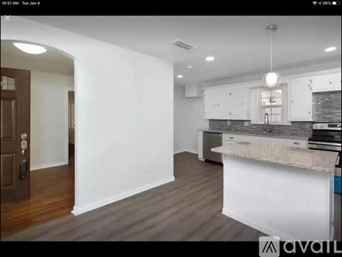 A modern kitchen with white cabinets and a wooden floor.