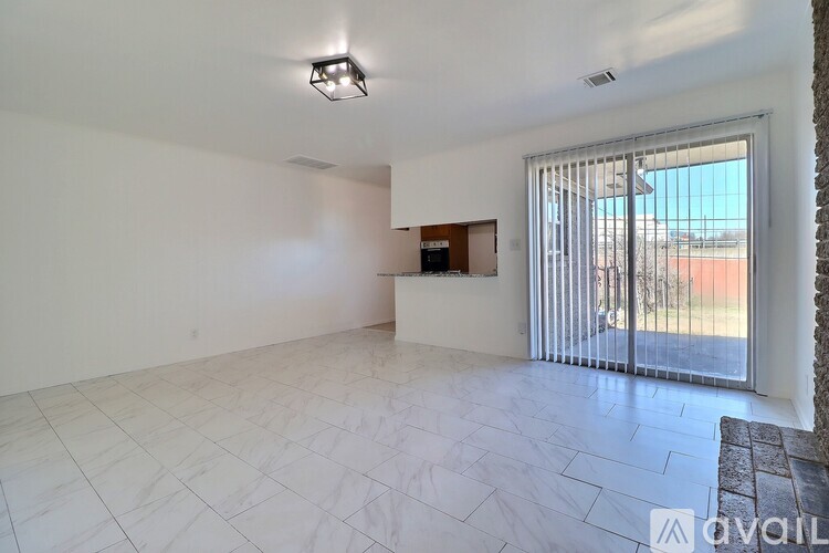 A spacious room with a marble floor and a sliding glass door leading to a balcony.