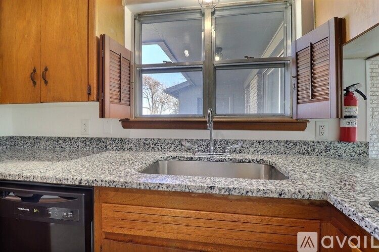 A kitchen with a granite countertop and wooden cabinets.