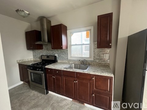 A kitchen with brown cabinets and a black refrigerator.