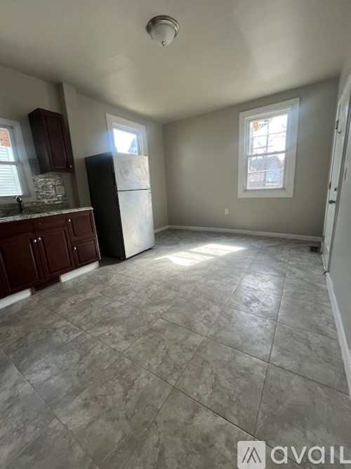 A kitchen with a black refrigerator and a tiled floor.
