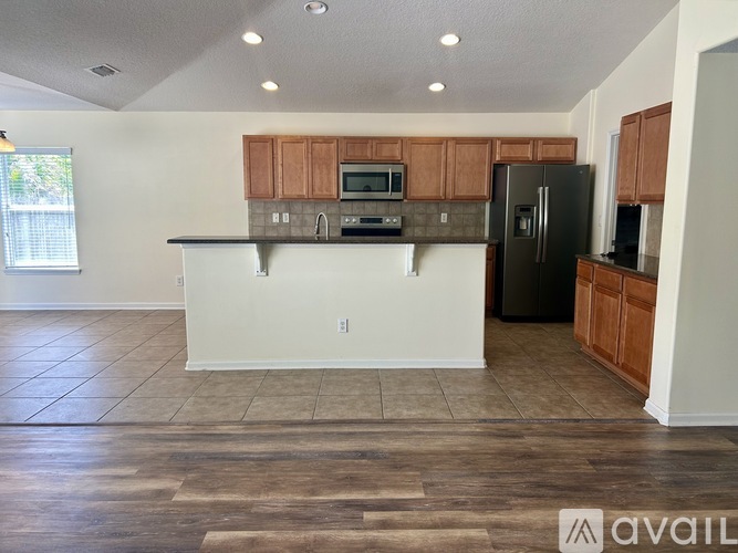 A kitchen with wooden cabinets and a black refrigerator.