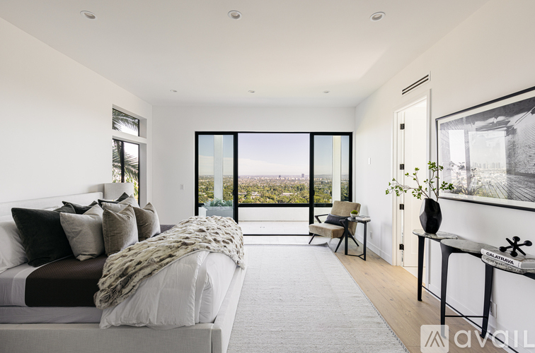 A modern bedroom with a large bed and a view of the city.