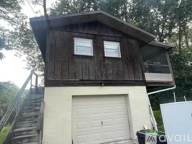 A wooden house with a white garage door and a sign that says "AVAILABLE".