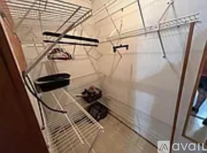 A kitchen with a white wall and a metal rack with a pot and a pan.
