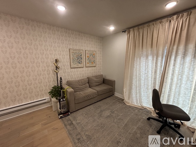 A living room with a couch, a chair, and a vacuum cleaner.