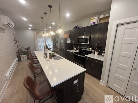 A kitchen with a white countertop and brown chairs.