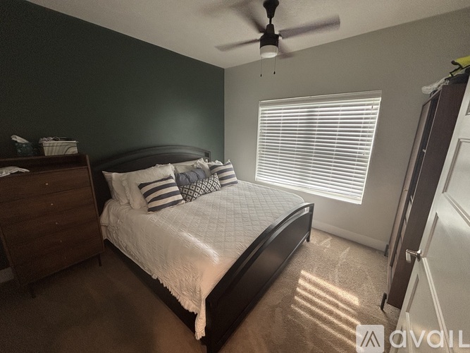 A bedroom with a bed, dresser, and ceiling fan.