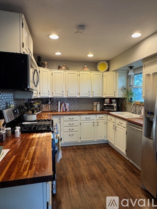 A kitchen with white cabinets and a wooden counter top.