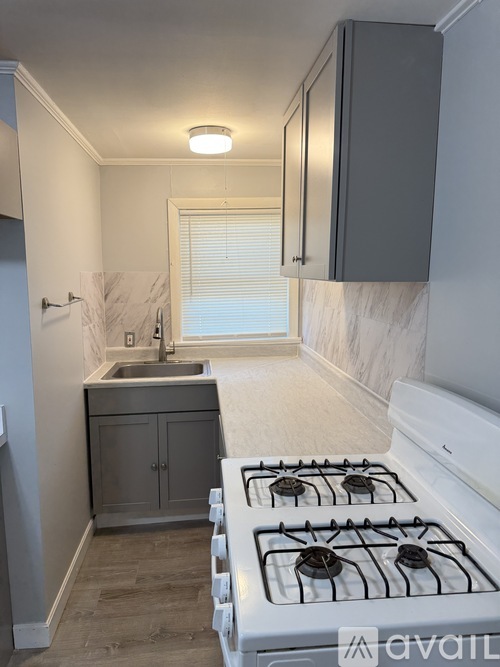 A kitchen with a white gas stove and a marble countertop.