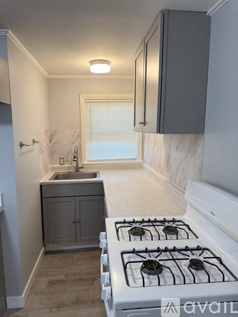 A kitchen with a white gas stove and a marble countertop.