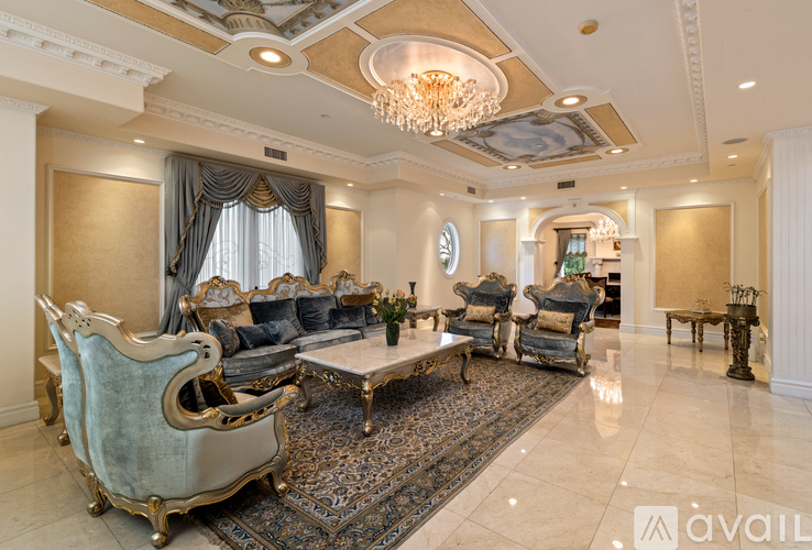 A living room with a large rug and a chandelier.
