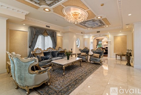 A living room with a large rug and a chandelier.