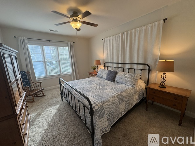A bedroom with a bed, a ceiling fan, and a window with curtains.