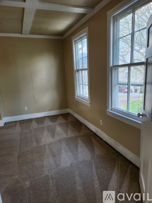 A room with two windows and carpeted floor.