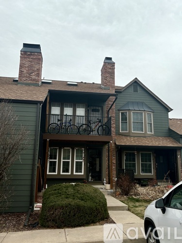 A house with a balcony and a white car parked in front.