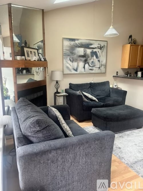 A living room with a grey couch and a painting on the wall.
