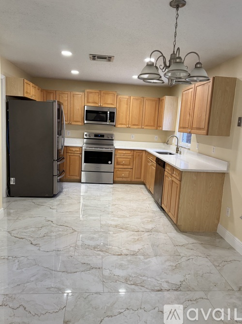 A kitchen with wooden cabinets and marble flooring.