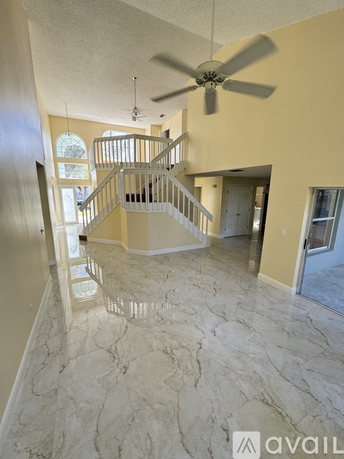 A spacious living room with a marble floor and a staircase with a metal railing.