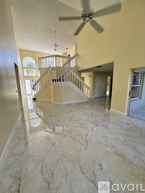 A spacious room with a marble floor and a ceiling fan.