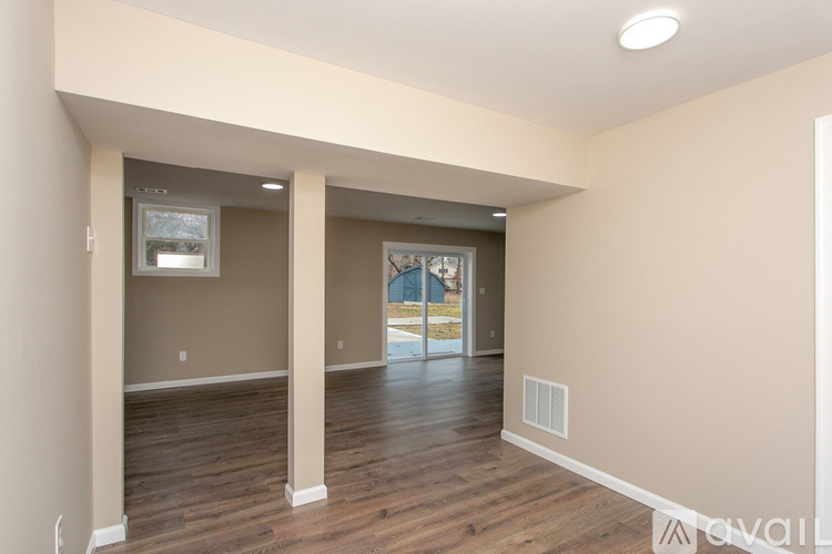 A spacious room with wooden floors and a large window.