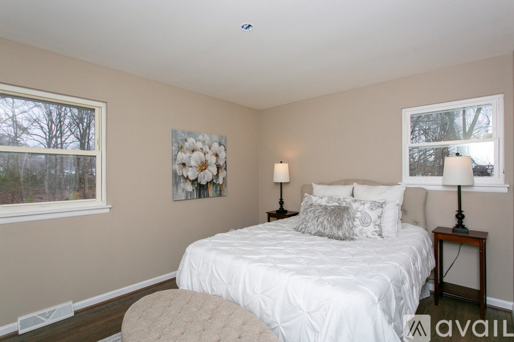A bedroom with a bed, two lamps, and a painting on the wall.