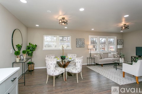 A well-lit living room with a dining table set for two and a couch.