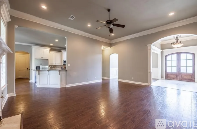 A spacious living room with wood flooring and a ceiling fan.