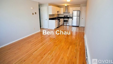 A kitchen with white cabinets and a wooden floor.
