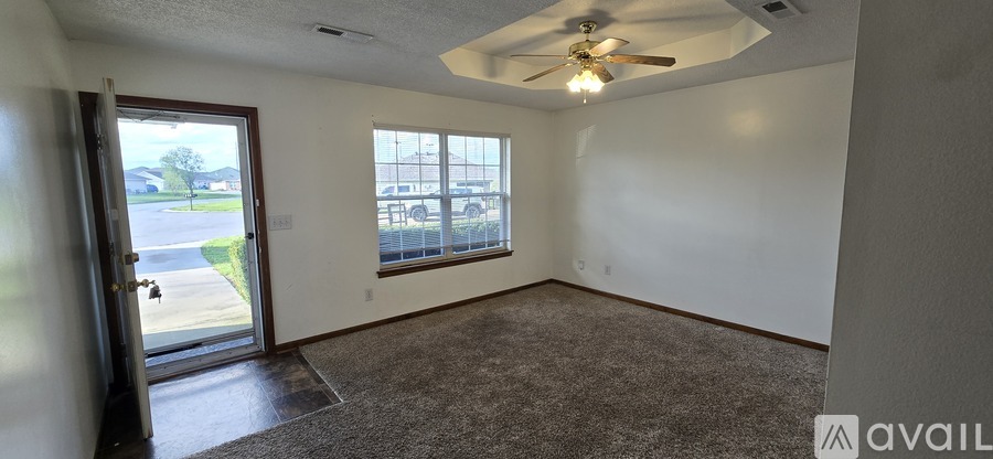 A room with a ceiling fan and a door leading outside.