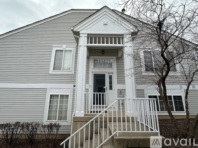 A house with a grey siding and a white front door.