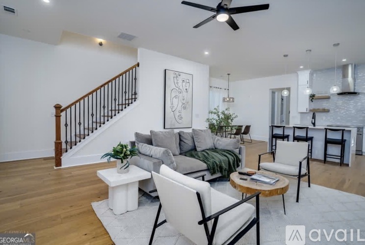 A living room with a staircase, a sofa, a coffee table, and a ceiling fan.
