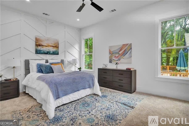 A bedroom with a large bed, a ceiling fan, and a rug on the floor.