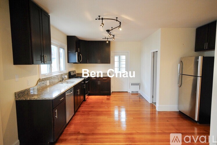 A kitchen with black cabinets and a wooden floor.