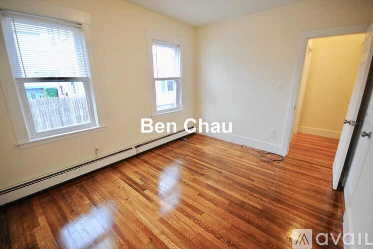A room with wooden floors and two windows, one of which is open.