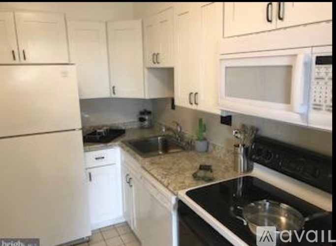 A kitchen with white cabinets and black appliances.