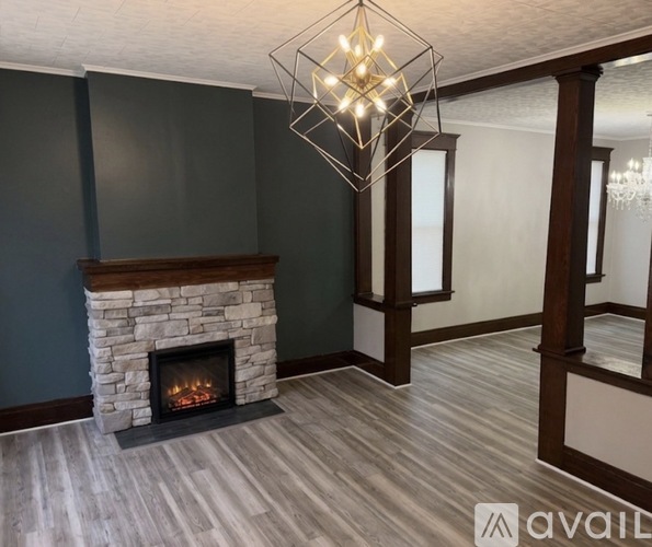 A modern living room with a stone fireplace and a chandelier.