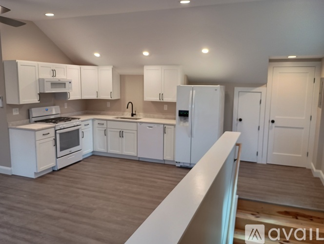 A kitchen with white cabinets and appliances is available for rent.